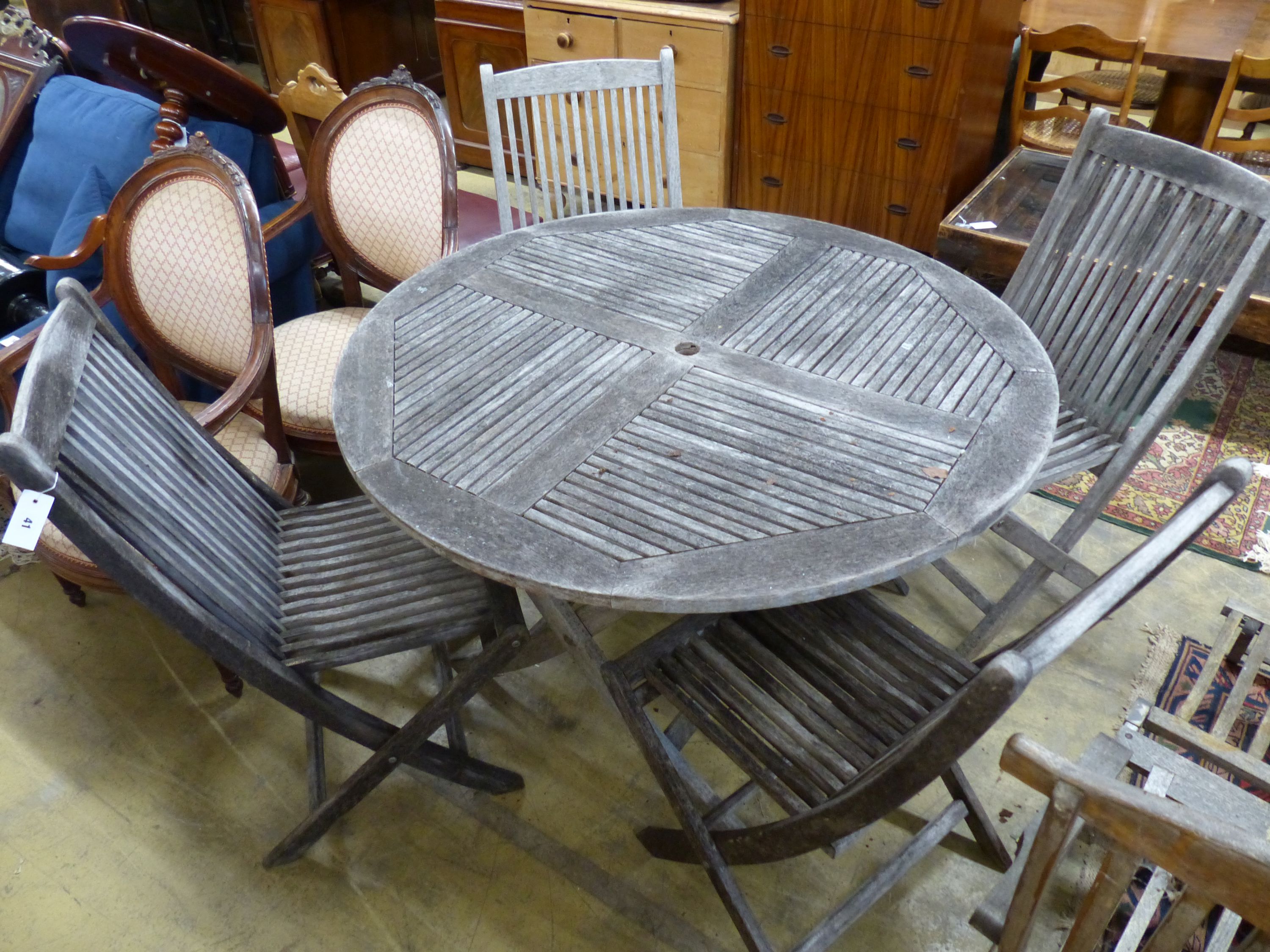 A teak garden table, 125cm diameter and four matching chairs, all folding